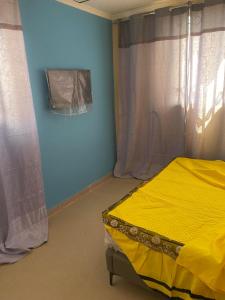 a bedroom with a yellow bed and blue walls at Hotel Mardoche Banto in Luanda
