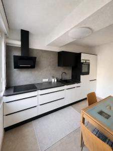 a kitchen with white cabinets and a black counter top at Four Rooms Allgäu Apartment in Wangen im Allgäu