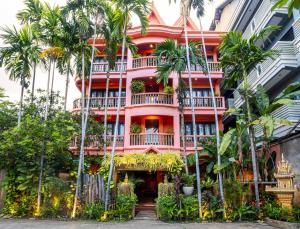 a pink building with palm trees in front of it at Golden Butterfly Villa in Siem Reap