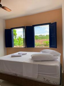 a bedroom with a large bed with two windows at Pousada da Cida in Lençóis