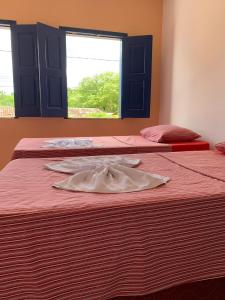 two beds in a room with a robe on them at Pousada da Cida in Lençóis +1 photo