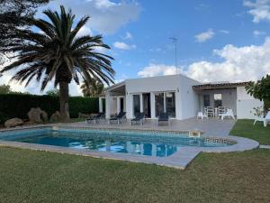 a villa with a swimming pool in front of a house at Casa SONEA private access to Cala nBrut. in Cala en Blanes