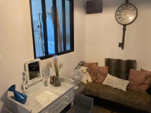 a living room with a couch and a clock on the wall at Bienvenue chez Chris ! in Saint-Hilaire-des-Landes