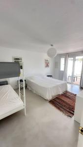 a white bedroom with two beds and a rug at House close to the beach of Punta Prima in Punta Prima
