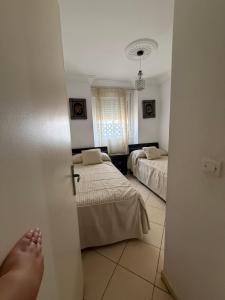 a room with two beds and a persons foot in the door at Beautiful appartement in Tétouan