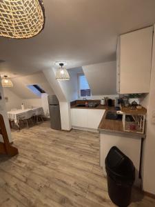 a kitchen with white cabinets and a wooden floor at Le Cocon in Boulogne-sur-Mer