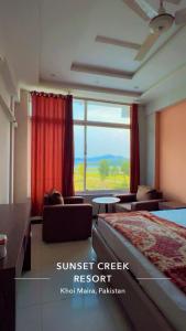 a bedroom with a bed and a large window at Sunset Creek in Harīpur