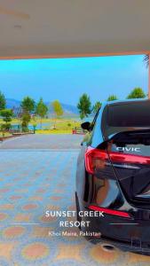 a rear view of a car parked in a parking lot at Sunset Creek in Harīpur