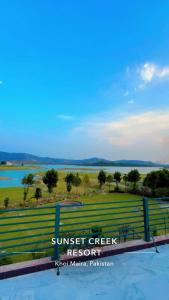 a sign for sunset creek resort with a view of the water at Sunset Creek in Harīpur