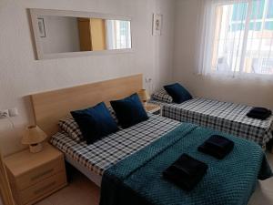 a bedroom with two beds with blue pillows and a mirror at Apartament La Mata "FELIZ" in La Mata