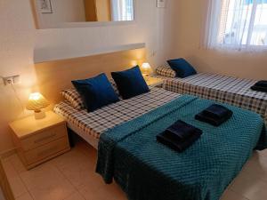 two beds in a room with blue pillows on them at Apartament La Mata "FELIZ" in La Mata