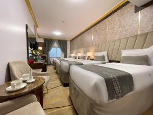 a hotel room with a row of beds and chairs at ODST AL Madinah Hotel - فندق اودست المدينة in Medina