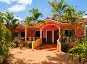a red house with palm trees in front of it at Royalstar Resort in Vagator