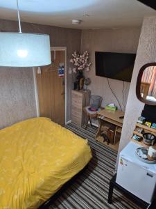 a bedroom with a yellow bed and a desk at Levens Terrace, Barrow Spa Therapy in Barrow in Furness