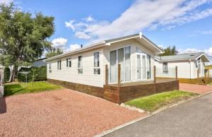 a white house with a brick driveway at 21 Hesket Park HUGE HOT TUB Pet friendly No Commercial Vans in High Hesket