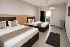 a hotel room with two beds and a balcony at Hotel Not Dot in north GOA in Calangute