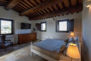 a bedroom with a bed and a chair and windows at Peaceful Umbria views & heated infinity pool in Umbertide