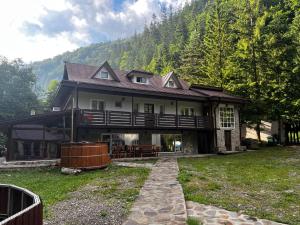 ein großes Haus mit Veranda auf einem Rasenfeld in der Unterkunft Mountain FIsh in Bicaz