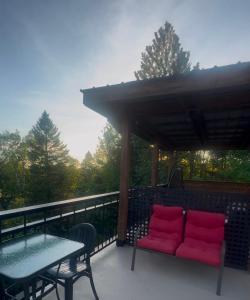 a patio with red chairs and a table on a deck at La Spacieuse Riverstone CITQ3O1849 in Saint Pierre de Broughton