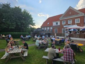 a group of people sitting at tables in a yard at Nissum Fjord Camping in Fjand Gårde