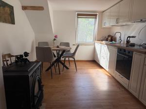 a kitchen with white cabinets and a table with chairs at Butas Prie Marių in Juodkrantė