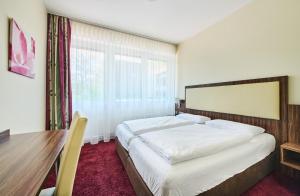 a bedroom with a bed and a table and a window at Hotel am Gröbenbach in Gröbenzell +19 photos