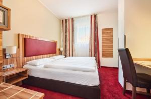 a hotel room with a bed and a desk at Hotel am Gröbenbach in Gröbenzell