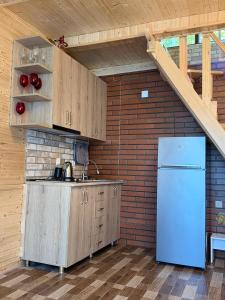a kitchen with a refrigerator and a brick wall at Guri's hut in Kirnat'i