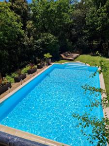 a large blue swimming pool in a yard at Rêve de roulotte in Apt
