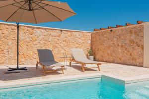 two chairs and an umbrella next to a swimming pool at Villa Lapidea in Vodice