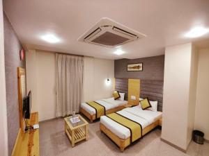a hotel room with two beds and a television at Hotel Darshan Inn in Anand