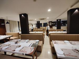a restaurant with white tables and a man standing in the background at Hotel Darshan Inn in Anand +18 photos
