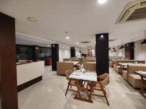 a dining room with a white table and chairs at Hotel Darshan Inn in Anand