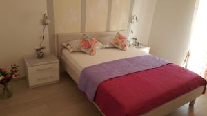 フヴァルにあるアパートメンツ テオのベッドルーム1室(ピンクと紫のシーツが備わるベッド1台付)