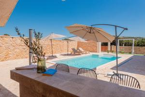 a table with chairs and an umbrella next to a pool at Villa Lapidea in Vodice