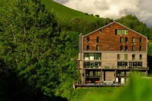 a large brick building on a hill with trees at Hotel Roshe Gudauri in Gudauri