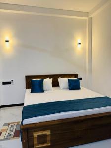 a bedroom with a large bed with blue pillows at Villa Calista Weligama in Weligama