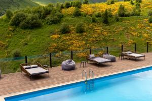 a wooden deck with chairs and a swimming pool at Hotel Roshe Gudauri in Gudauri