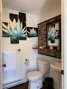 a bathroom with a toilet and paintings on the wall at La Spacieuse Riverstone CITQ3O1849 in Saint Pierre de Broughton +34 photos