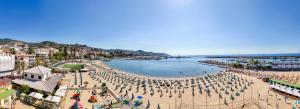 a beach with a crowd of people and umbrellas at Residence Dei Due Porti in Sanremo