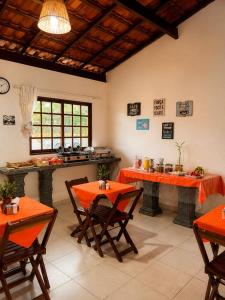 a kitchen with orange tables and chairs in a room at Torre do Sol in Praia do Frances