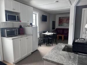 a kitchen with white cabinets and a table with a dining room at La Spacieuse Riverstone CITQ3O1849 in Saint Pierre de Broughton