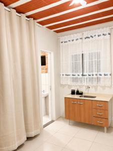a bathroom with white curtains and a sink and a window at Studio completo em Diamantina-MG in Diamantina