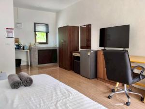 a room with a bed with a chair and a television at First light beach bungalow in Ko Phangan