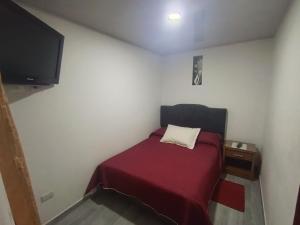 a small bedroom with a bed with a red blanket and a tv at Casa Bercel in Choachí +11 photos