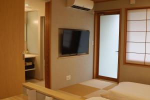 a room with a flat screen tv on the wall at Kansai Airport Hotel Pine Villa in Kansai International Airport
