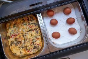 a pan with a pizza with eggs on it at Mila Sissi Bay Hotel in Sisi
