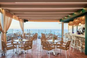 a restaurant with tables and chairs and a view of the ocean at Mila Sissi Bay Hotel in Sisi