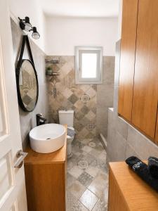 a bathroom with a sink and a toilet and a mirror at NŌSSA Boutique Apartment in Naousa +7 photos