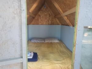 a small bed in a room with a roof at Micro Africa Camping Site in Delvinë